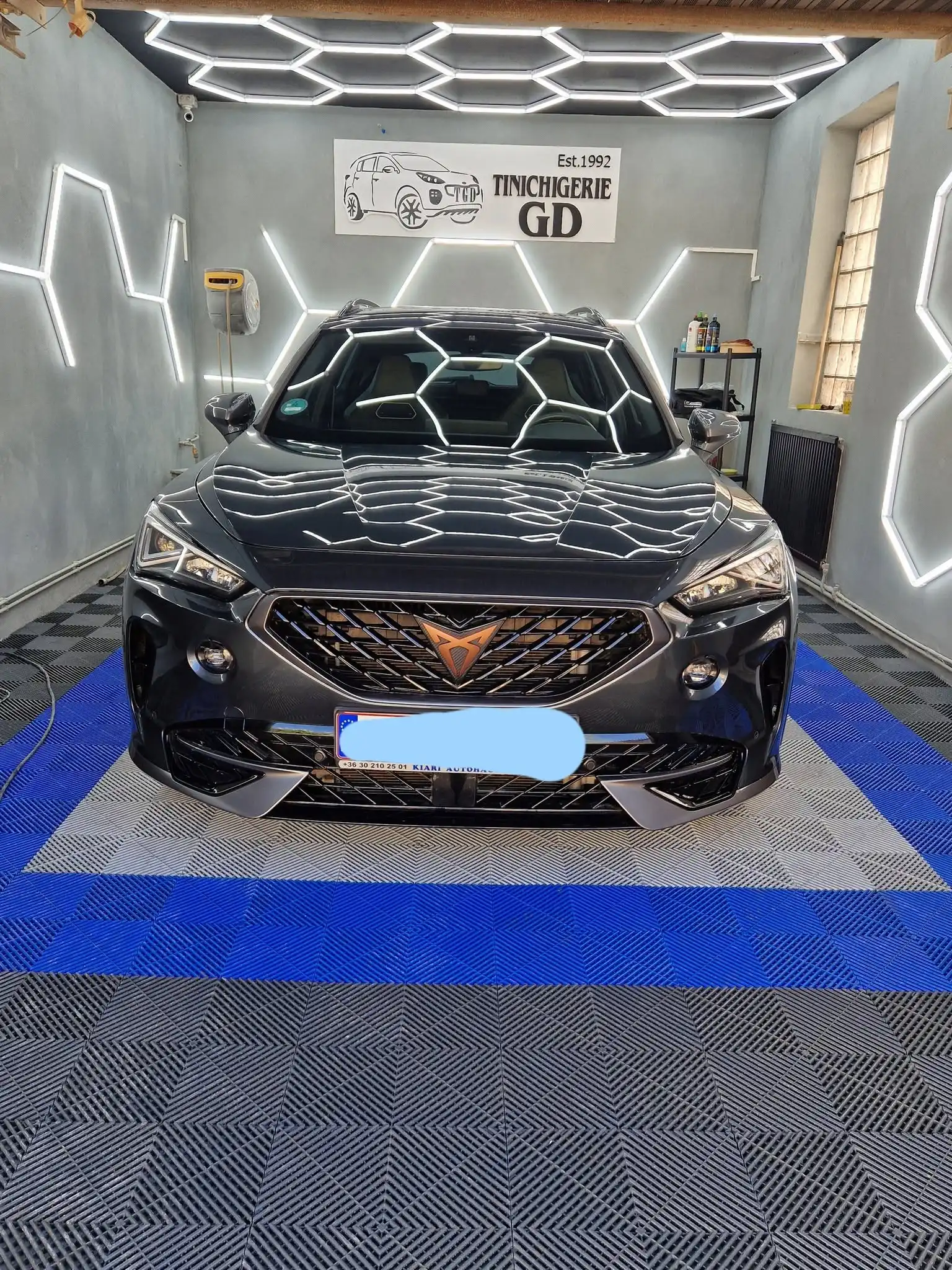 Reflexii ale luminilor atelierului pe capota unui autoturism