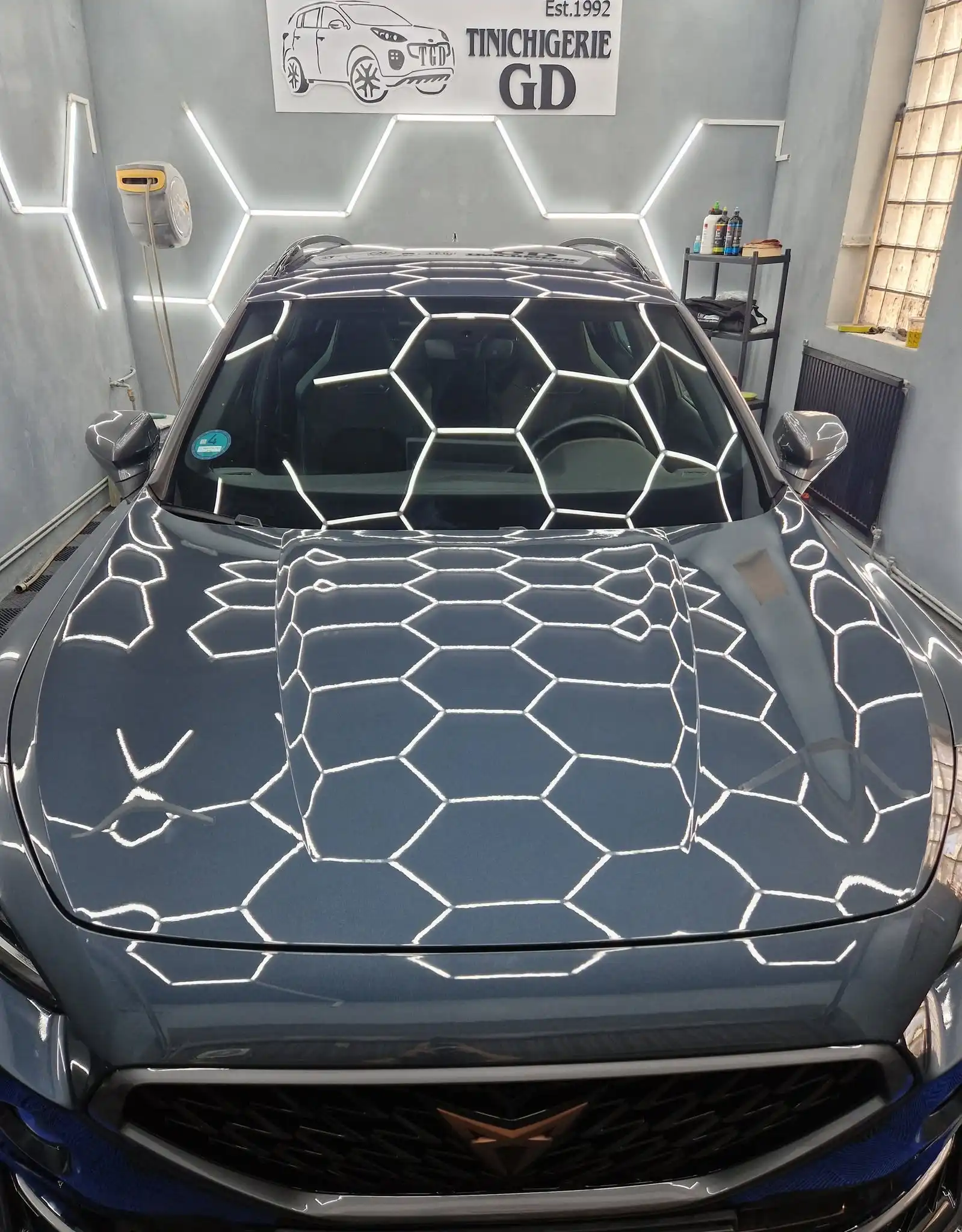 Reflexii ale iluminatului de atelier pe capota unui autoturism