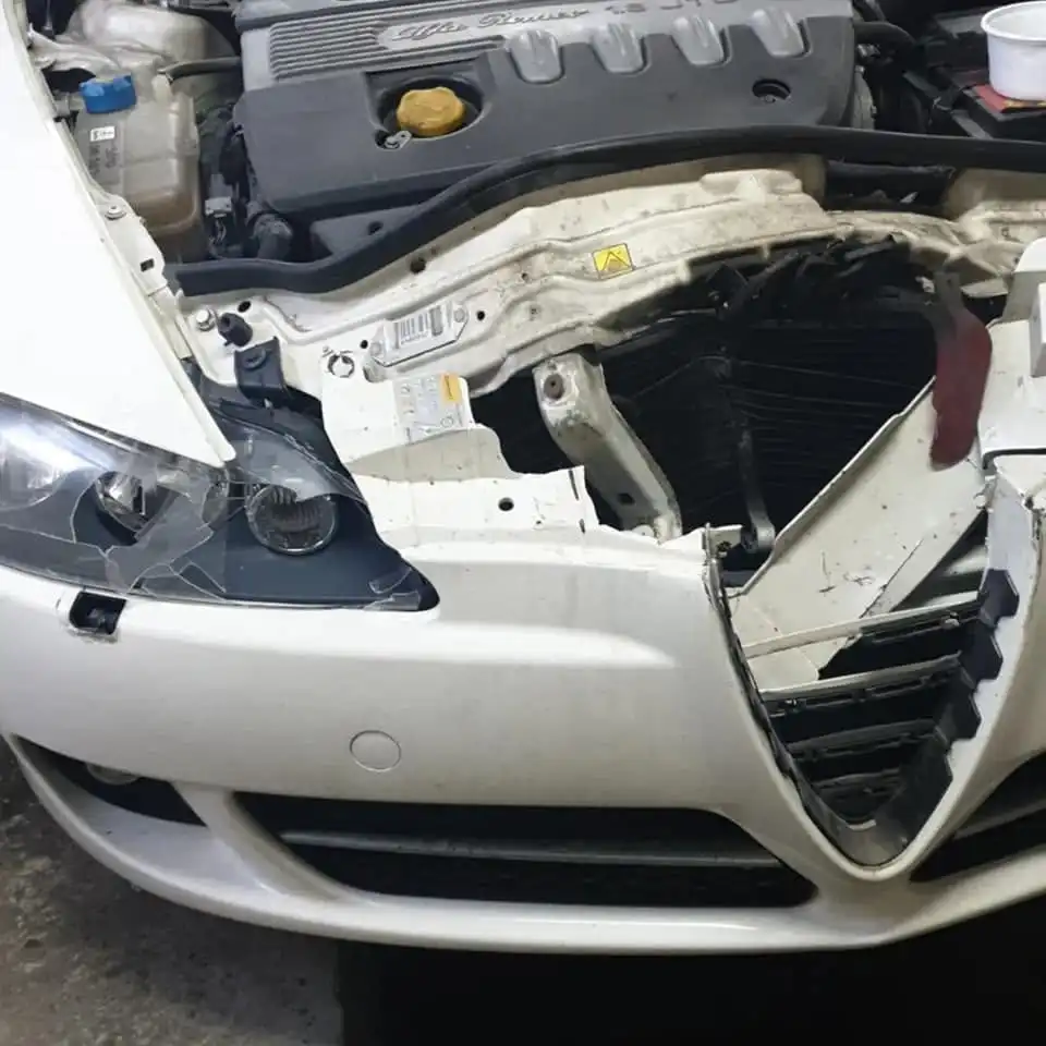 Alfa Romeo cu partea frontală avariată și elemente demontate înaintea reparației
